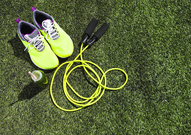 Running shoes, jump rope and drink bottle with green juice  - Photo, Image