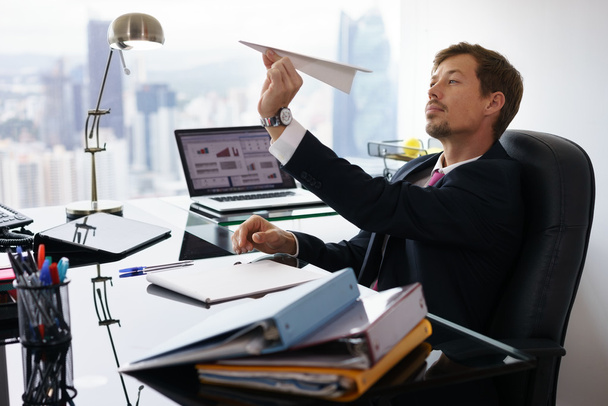 Aborrecido branco colarinho trabalhador jogando avião de papel no escritório
 - Foto, Imagem