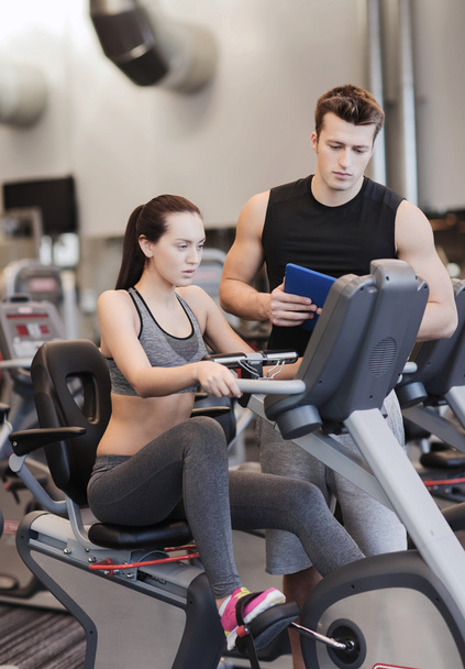 woman with trainer on exercise bike in gym - Foto, immagini