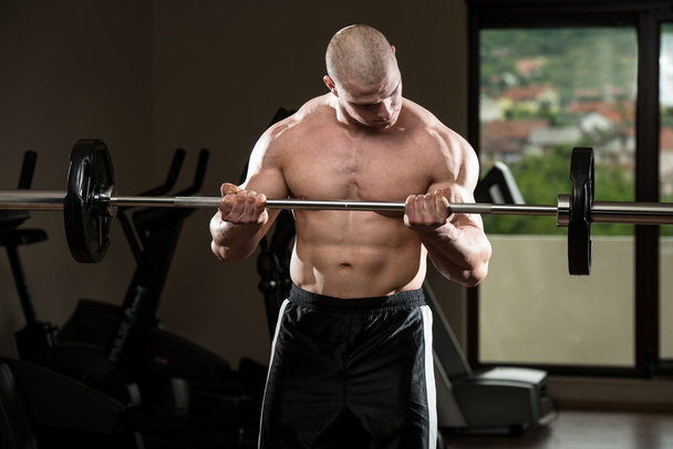 Man In The Gym Exercising Biceps With Barbell - Foto, Imagen