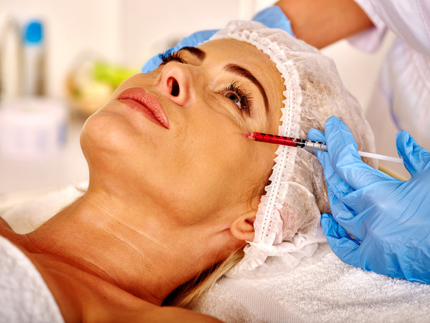 Женщина средних лет в салон красоты с косметологом. Женщина делает инъекции ботокса
. - Фото, изображение