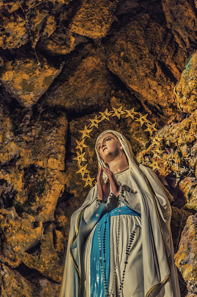 Aparición de la Virgen María rodeada de estrellas en la gruta de Lourdes
 - Foto, Imagen