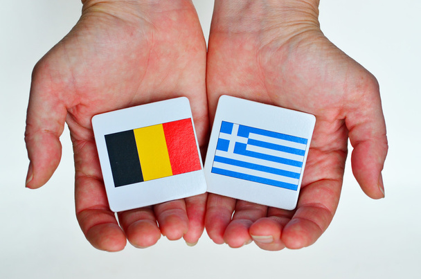 Δύο χέρια κατέχει τις εθνικές σημαίες της Γερμανίας (L) και Ελλάδα (R) - Φωτογραφία, εικόνα