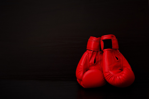 Two red boxing gloves on the side of the frame on a black background, empty space - Φωτογραφία, εικόνα