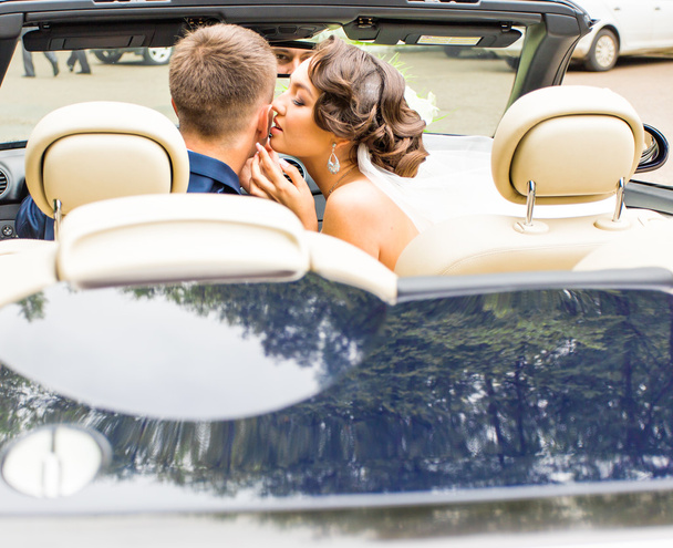 Beautiful young couple bride and groom posing in cabriolet - Photo, Image