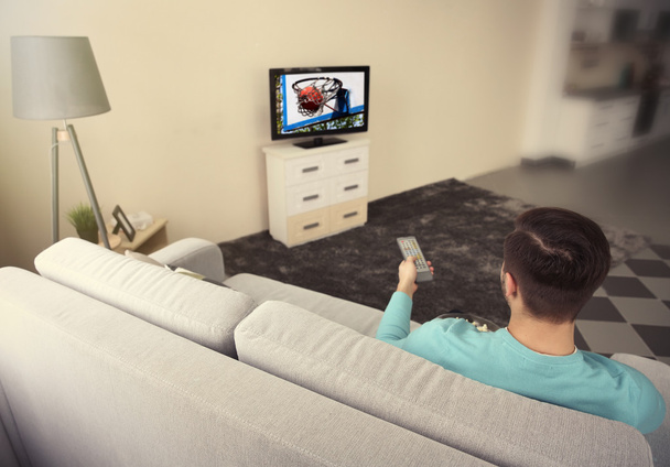 Young man watching TV at home - Фото, зображення