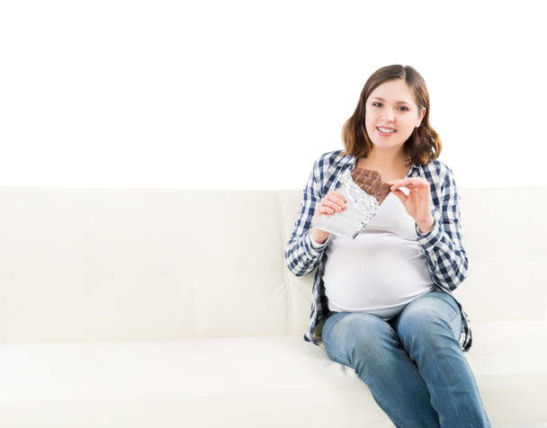 Attractive young pregnant woman having a bite of chocolate - Photo, Image