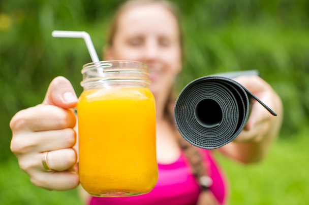 Fitness woman with yoga mat holding a glass of orange juice - Fotó, kép