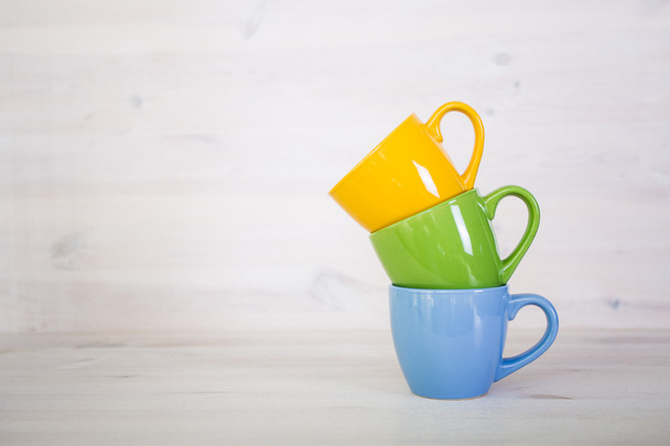 stack of colorful coffee cups on a white wooden background - Foto, Imagem