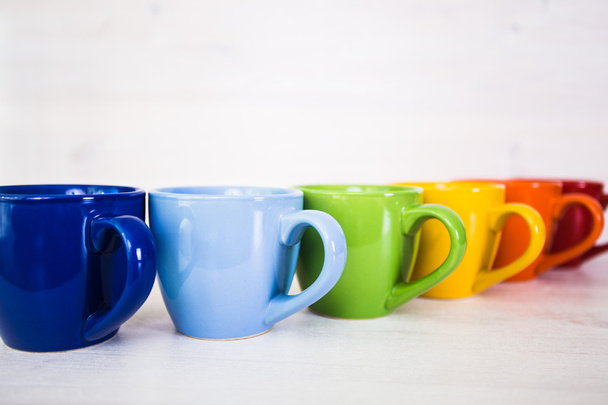 stack of colorful coffee cups on a white wooden background - Photo, Image