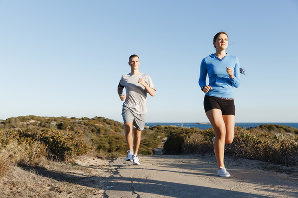 Urheilu juoksija lenkkeily rannalla treenata hänen kumppaninsa kanssa
 - Valokuva, kuva