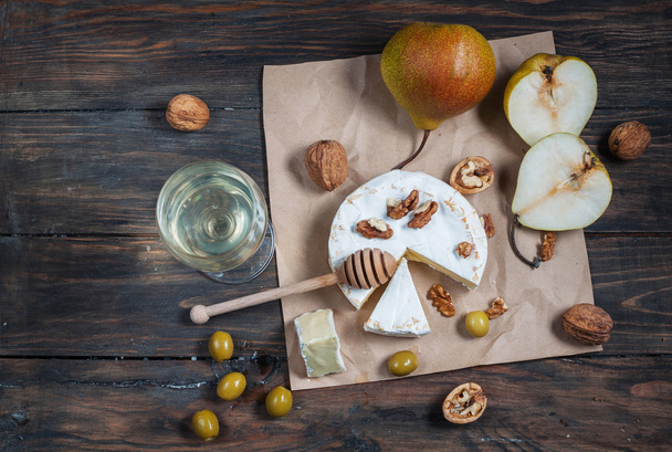 カマンベール チーズにくるみとはちみつと素朴なテーブルに梨。白ワインのガラス - 写真・画像