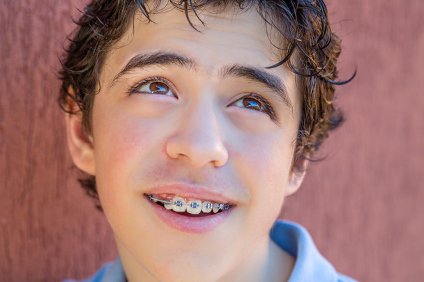 jeune garçon souriant avec des bretelles tout en regardant vers son côté supérieur gauche
 - Photo, image