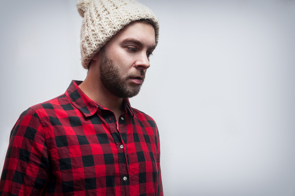 Brutale bebaarde man dragen van gebreide cap en geruite shirt - Foto, afbeelding