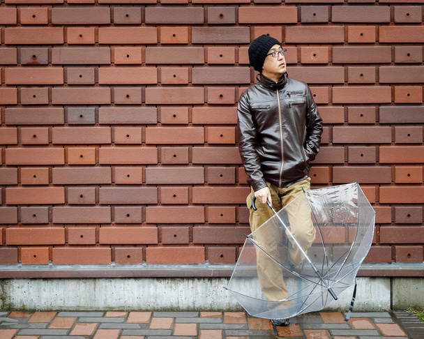 Азиат в коричневой куртке с прозрачным зонтиком
 - Фото, изображение