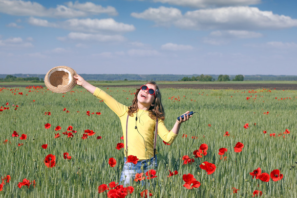 heureuse petite fille écouter de la musique sur le téléphone dans la prairie
 - Photo, image