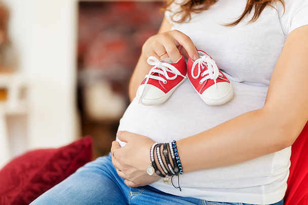 Mujer embarazada con zapatos de bebé en la mano - Foto, imagen