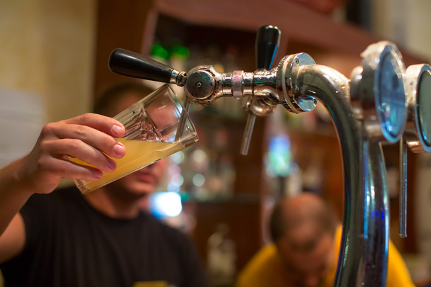 バーテンダーは、バーでグラスにビールを注ぐ - 写真・画像