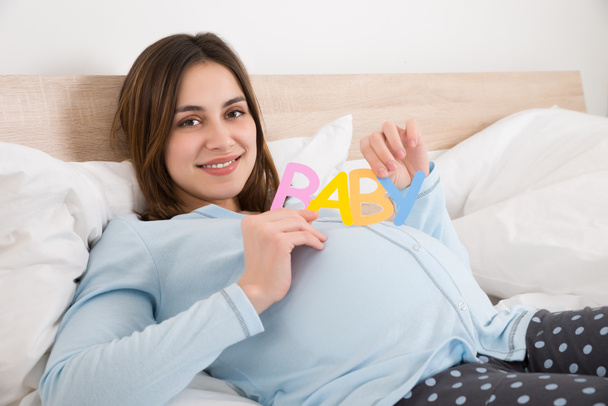 ベッドの上の妊娠中の女性 - 写真・画像