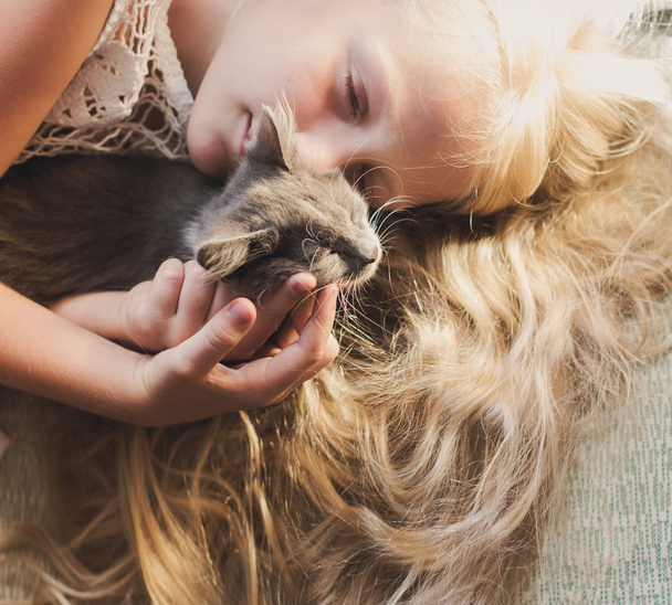 Baby girl holding hands a kitten in the light of sunset, pet, friend, - Photo, Image