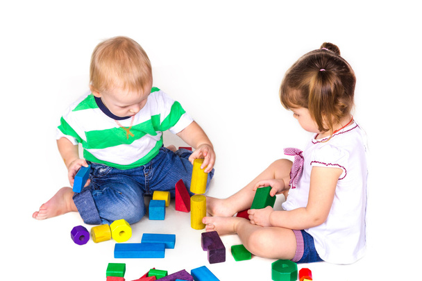 Счастливые дети играют со строительными блоками, изолированными на белом. Командная работа, творческая концепция. - Фото, изображение