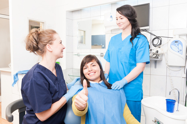 Paciente atraente e equipe médica em consultório odontológico polegar para cima
 - Foto, Imagem