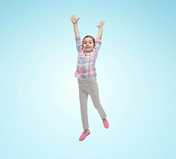happy little girl jumping in air over blue - Zdjęcie, obraz