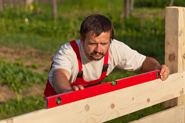 Trabalhador construção de cerca de madeira
 - Foto, Imagem