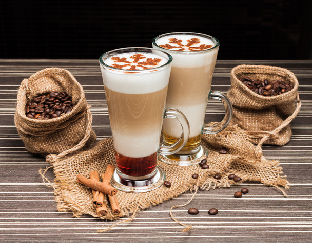 Copa de café de vidrio transparente y granos de café sobre tela de arpillera y fondo marrón
. - Foto, Imagen