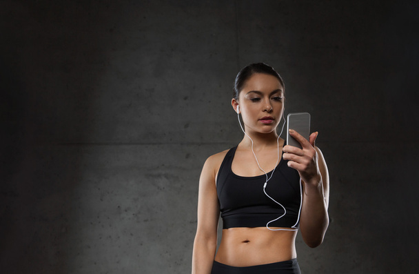 woman with smartphone and earphones in gym - Фото, изображение