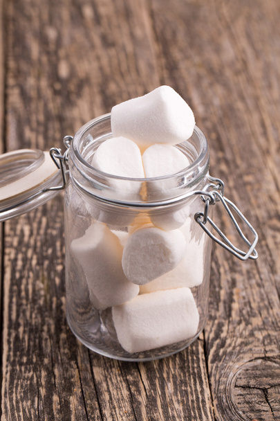 Dolci marshmallow in un barattolo di vetro su un tavolo di legno
. - Foto, immagini