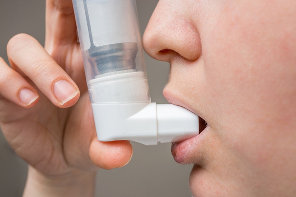 Face of woman suffering from asthma using inhaler. - Fotó, kép