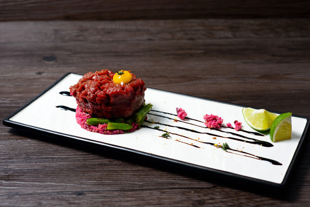 Tartar of beef served with lime on white dish - Photo, Image