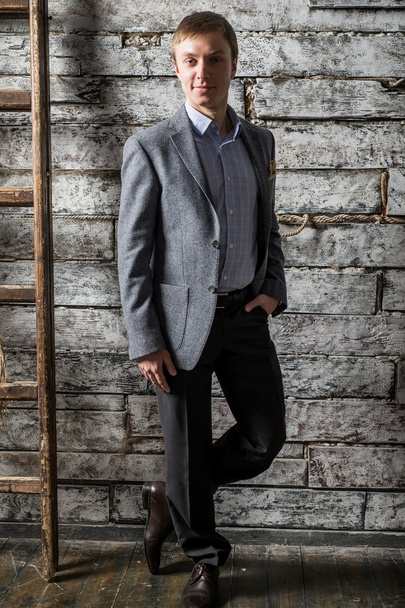 A young man in a gray business suit and light shirt standing in full length on studio shooting - Foto, Imagem
