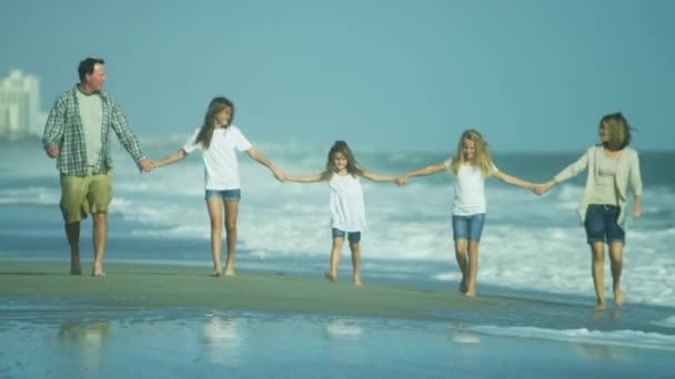 Padres con hijas caminando en la playa
 - Metraje, vídeo