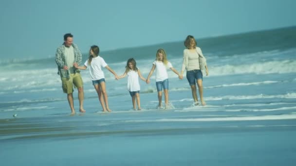 Vanhemmat tyttäriensä kanssa kävelemässä rannalla
 - Materiaali, video