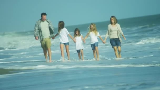 Padres con hijas caminando en la playa
 - Metraje, vídeo