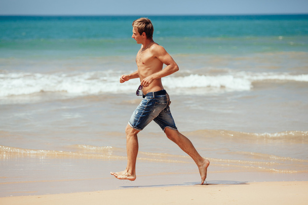 Man running on the beach with the sea in the background. Male ru - Photo, image