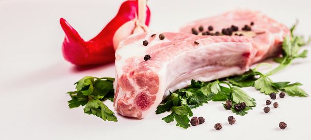 juicy piece of meat on the bone with a pod of red pepper, parsley and garlic lie on a wooden table. - Fotoğraf, Görsel