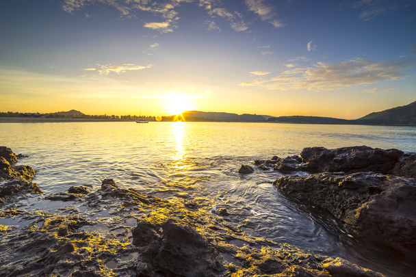 Пляжні скелі та водна хвиля з фоном сходу сонця
  - Фото, зображення