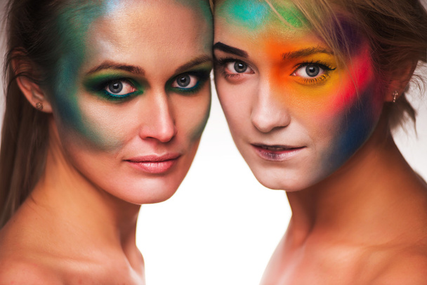 Belleza cósmica. Retrato de dos hermosas mujeres con maquillaje artístico posando con plumas fondo blanco
 - Foto, Imagen