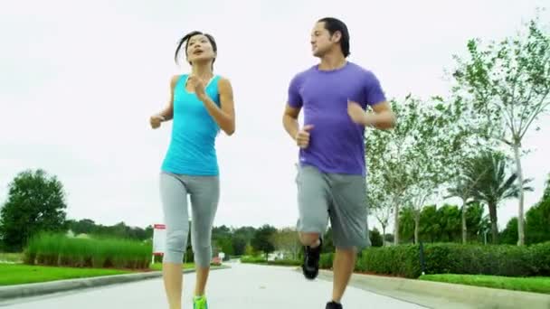 Paar in sportkleding joggen in het park - Video