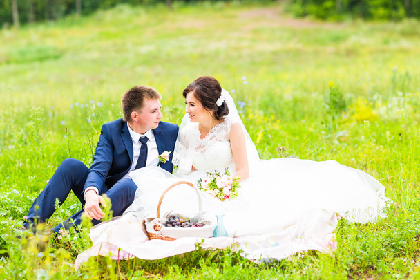 Happy young wedding couple on picnic in park - Photo, Image