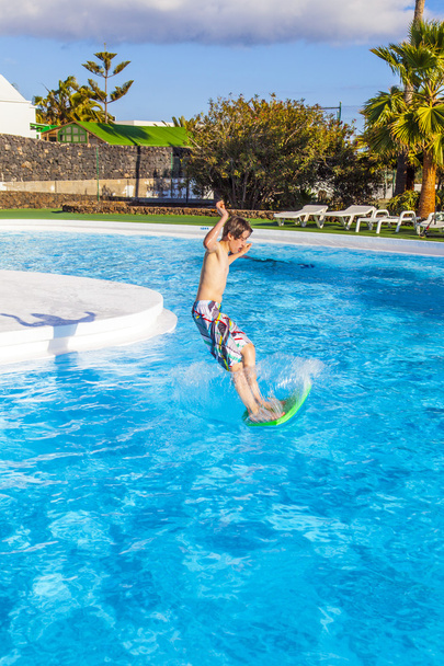 хлопчик стрибає у блакитному басейні
 - Фото, зображення