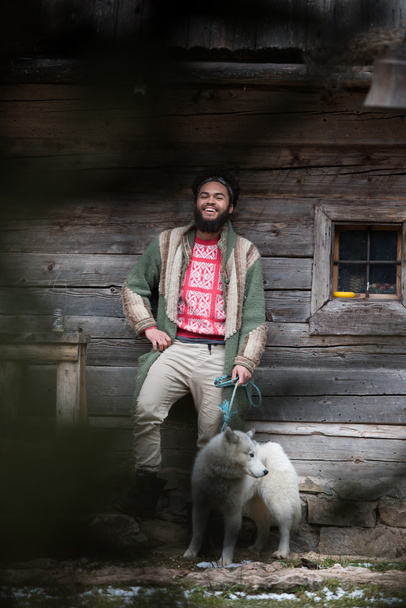 hipster with dog in front of wooden house - Fotó, kép