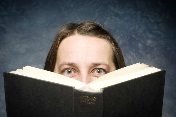 Happy zralá žena schovává za knihu na modrém pozadí. - Fotografie, Obrázek