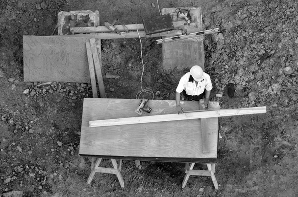 Obrero de la construcción mide pieza de madera con regla
 - Foto, Imagen