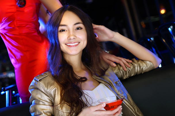 ドリンクを飲みながら夜のクラブで魅力的な女性 - 写真・画像