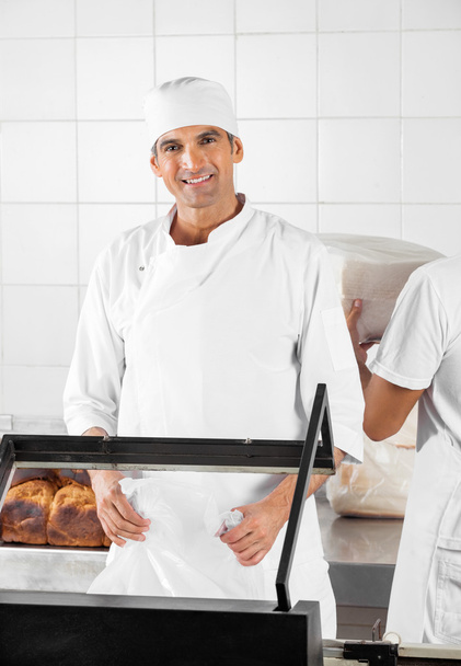 Smiling Baker Packing Breads In Bakery - Foto, immagini