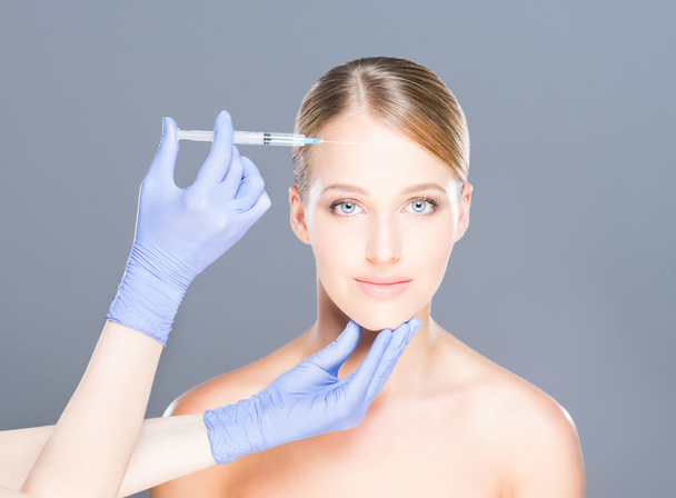 Arts injecteren Botox in een mooi gezicht van een jonge vrouw - Foto, afbeelding